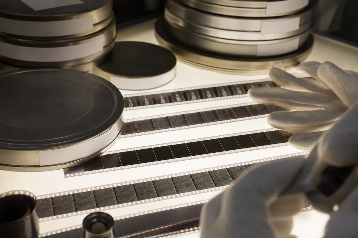 Bobines de pellicule 35 mm et boîtes métalliques posées sur une table lumineuse d&rsquo;archive